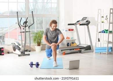 Sporty Young Man With Laptop Training In Gym