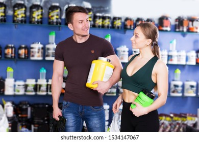 Sporty Young Pair Walking With Food Supplements Bought In Sport Nutrition Store