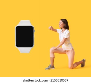 Sporty young woman checking her pulse and big smartwatch with blank screen on yellow background 