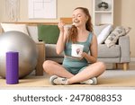 Sporty young woman eating ice cream at home