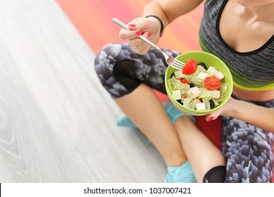 Sporty Young Woman Eating Salad After Fitness Training At Home