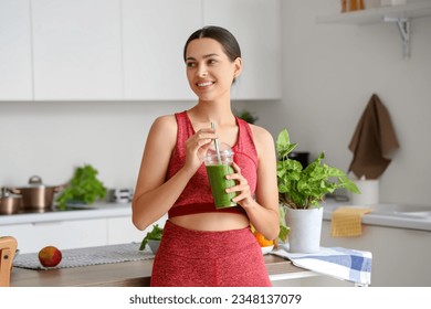 Sporty young woman with healthy smoothie in kitchen - Powered by Shutterstock