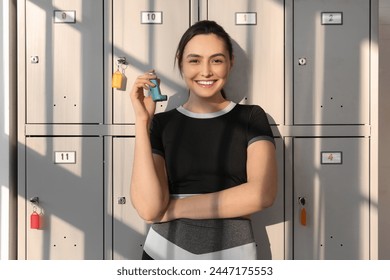 Sporty young woman with inhaler near locker in gym - Powered by Shutterstock