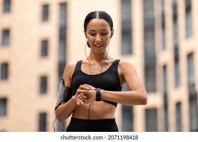 Sporty Young Woman Looking At Smartwatch On Her Wrist, Tracking Fitness Activity During Training Outdoors, Happy Fit Lady Using Modern Gadget For Checking Heart Rate Or Choosing Music For Jogging - Shutterstock ID 2071198418