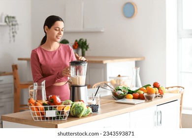 Sporty young woman making healthy smoothie with blender in kitchen - Powered by Shutterstock