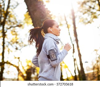 Sporty young woman running in the park and listening to music. Sport lifestyle. Motion blur. - Shutterstock ID 372703618