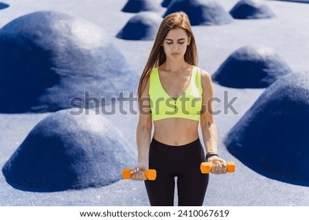 sporty young woman stretches with dumbbells by the waterfront, radiating health and vitality in an urban setting