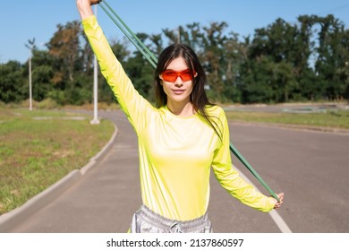 Sporty young woman with stretching tape on sunny day - Shutterstock ID 2137860597