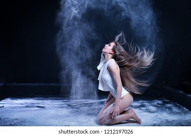 sporty young woman throws flour on black background