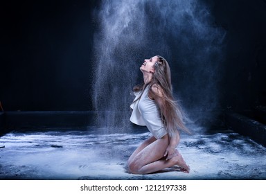 sporty young woman throws flour on black background