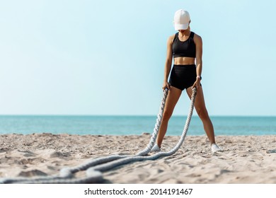 Sporty Young Woman Training With A Battle Rope, Man Doing Fitness Workout On The Beach On A Sunny Day Using Two Battle Ropes On The Beach