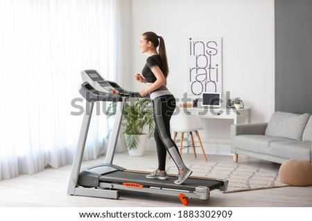 Sporty young woman training on treadmill at home