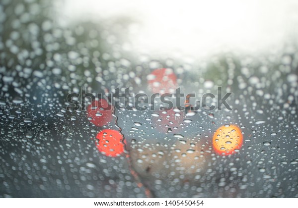 Spot focus  Drops\
of rain flowing into the car glass At the time of rain Blurred\
background as a car\
taillight.