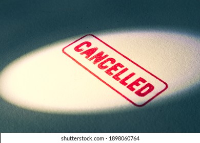 Spot light on red cancelled rubber stamp with dark shadow. Negative label on shadowy, dark background.  Cancel culture concept with noise and grain.Message on textured paper. Online shaming problem.