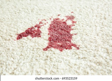 Spot of red wine on white carpet, close up