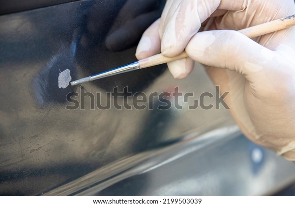 Spot tinting of chips with a brush.\
auto painter restores the paint layer of the\
car.