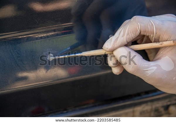 Spot tinting of chips with a brush.\
auto painter restores the paint layer of the\
car.