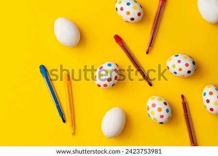 Spotty painted colorful easter eggs with felt tip colorig pens on yellow background. Directly above table top shot.