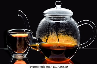 spout of beautifully shaped clear glass japanese teapot crossing round double sided modern clear teaglass filled with tea isolated on black - Powered by Shutterstock