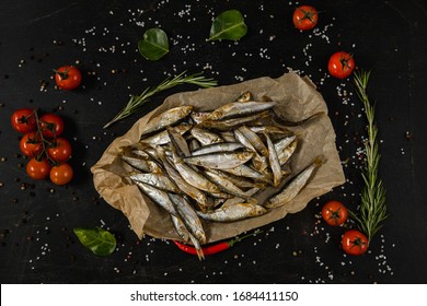 Sprats fish on kitchen board. Lemon,  lime, tomato, rosemary on dark background - Powered by Shutterstock