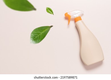 Spray Bottle With Cleaning Product On Light Background With Flying Green Leaves. Creative Eco Cleaning Concept. Environmentally Friendly Home And Office Cleaning