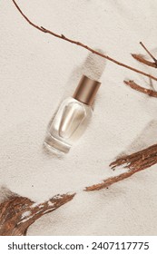 Spray bottle with empty label on natural sand top view, dry branches. Natural skincare or perfume product. Cosmetics for beauty routine. Minimal aesthetic.