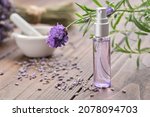 Spray bottle of lavender essential oil. Scented lavender water, serum, flavored water. Lavender flowers on background. Aromatherapy. Natural cosmetic beauty care product. Alternative herbal medicine.