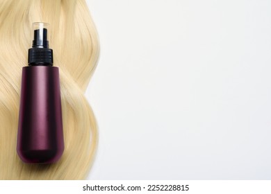Spray bottle with thermal protection and lock of blonde hair on white background, flat lay. Space for text - Shutterstock ID 2252228815