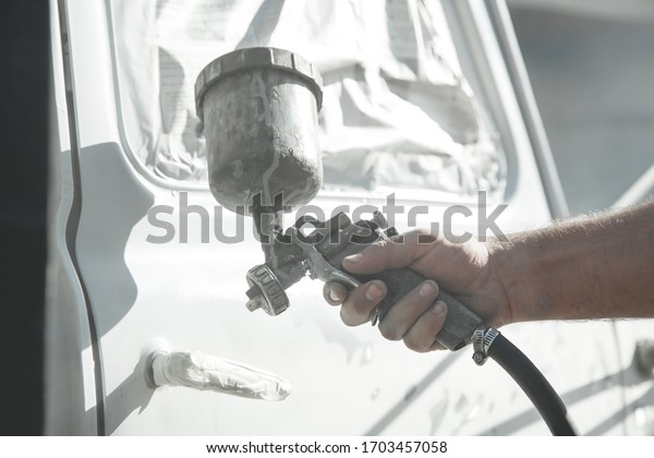 Spray\
gun in the hand of a painter. Painting car\
details