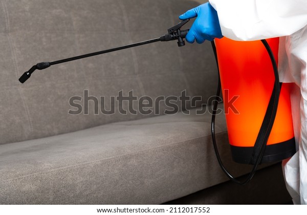 Spray\
gun with pesticides close-up. An exterminator in work clothes\
sprays pesticides from a spray bottle. Fight against insects in\
apartments and houses. Disinsection of\
premises.
