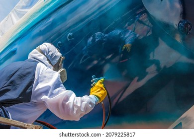 Spray Painter With Full Body Protection And Mask Painting The Hull Of Sailboat With High Gloss Varnish