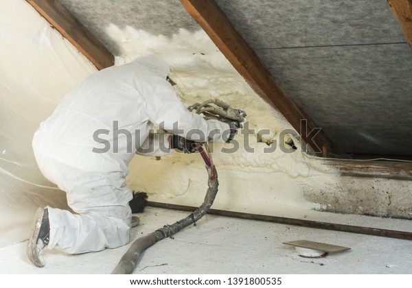 spray polyurethane foam for roof - technician\
spraying foam insulation using plural component gun for\
polyurethane foam, inside