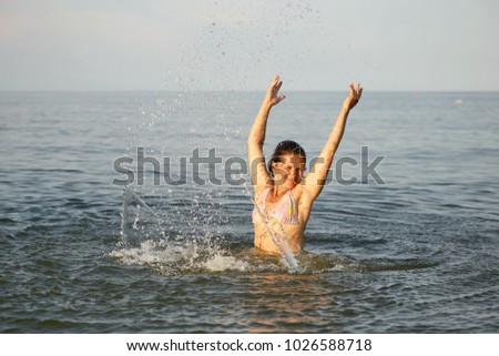 Spray with water. Girl having fun bathing in the sea