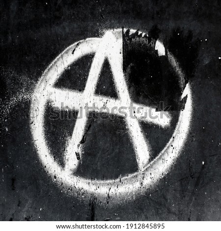 Sprayed anarchy symbol with overspray on grungy wall