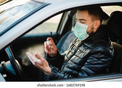 Spraying Anti-bacterial Sanitizer Spray On Hand In Car, Infection Control Concept. Sanitizer To Prevent Coronavirus, Covid-19, Flu. Spray Bottle. Man Wearing In Medical Protective Mask Driving A Car.