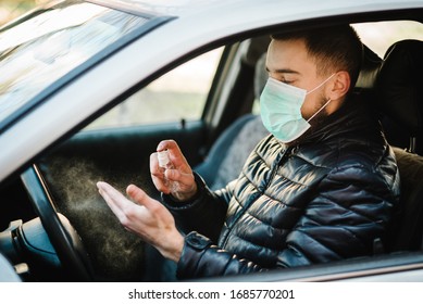 Spraying Anti-bacterial Sanitizer Spray On Hand In Car, Infection Control Concept. Sanitizer To Prevent Coronavirus, Covid-19, Flu. Spray Bottle. Man Wearing In Medical Protective Mask Driving A Car.