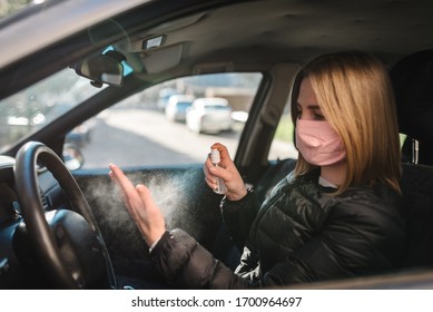 Spraying Antibacterial Sanitizer Spray On Hand In Car, Infection Control Concept. Sanitizer To Prevent Coronavirus, COVID-19, Flu. Spray Bottle. Woman Wearing In Medical Protective Mask Driving A Car.