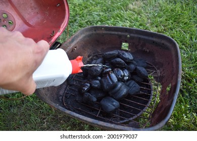 Spraying Lighter Fluid On Charcoal Briquettes