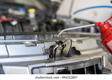 Spraying Lubricant On A Car Hood Hinge