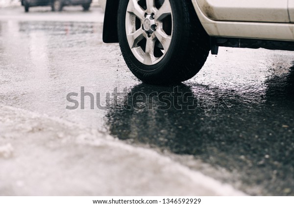 spraying water from\
the wheels of a car moving on a wet urban asphalt road. wet car\
wheel in the thaw. a car moving at speed through a puddle on a\
flooded city road during\
rain