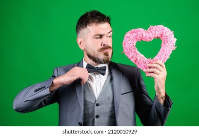 Spread Love. Happy In Love. Romantic Macho Flirting. Macho Looking For Girlfriend. Happy Valentines Day. Hipster Hold Heart Symbol Love. Man Formal Suit Celebrate Valentines Day Green Background