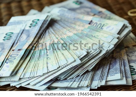 A spread of one hundred Rand notes cash South African Rands ZAR spread out on a textured table