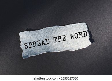 Spread the word - text on torn paper on dark desk in sunlight.