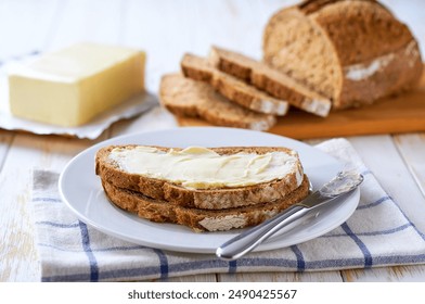 spreading butter in to crusty rye bread slices on a light kitchen table. - Powered by Shutterstock