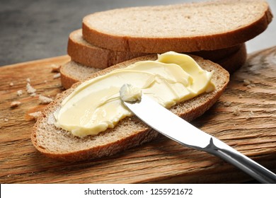 Spreading Butter Onto Toast With Knife On Wooden Board