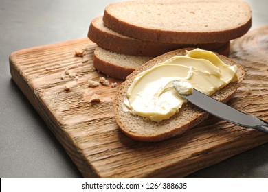 Spreading Butter Onto Toast With Knife On Wooden Board