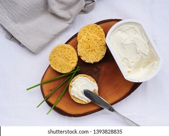 Spreading cream cheese on a slice of keto almond flour bread over wooden board