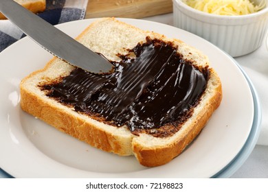 Spreading The Iconic Australian Spread Vegemite On To A Slice Of Fresh Bread.