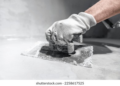 spreading the insulation on the concrete with a trowel - Shutterstock ID 2258617525