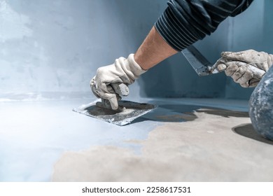spreading the insulation on the concrete with a trowel - Shutterstock ID 2258617531